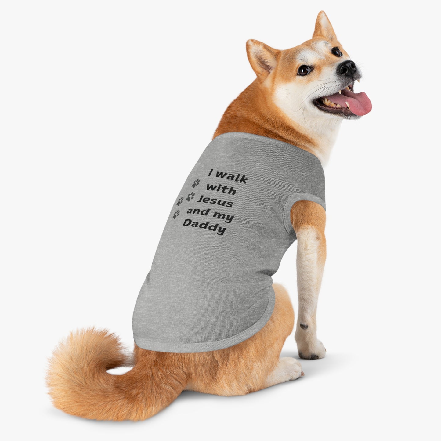 Shiba Inu dog wearing a grey shirt with the black text "I walk with Jesus and my daddy"