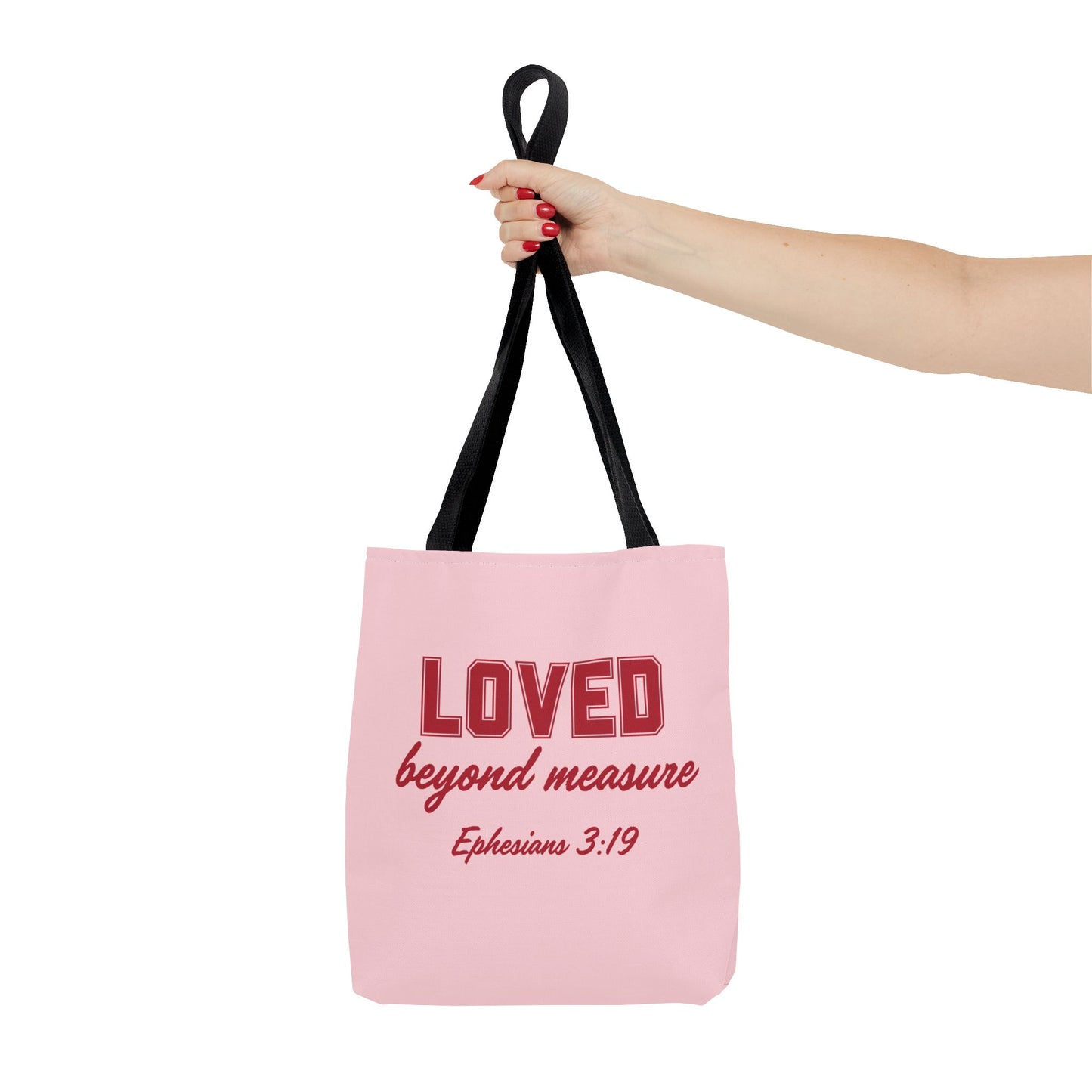 A pink tote bag with the text "LOVED beyond measure" and the Bible verse