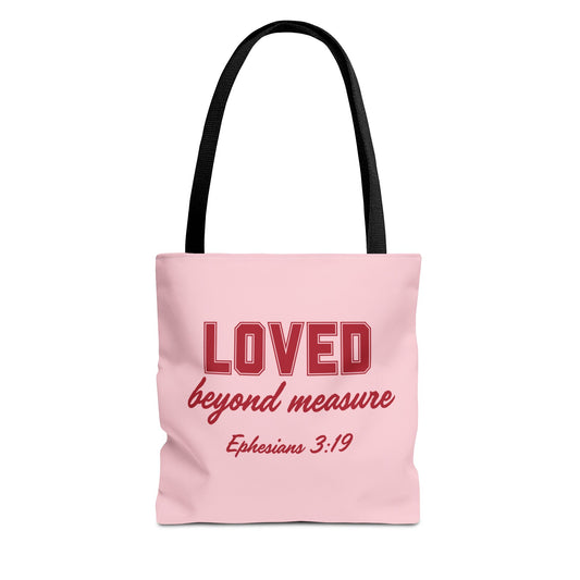 A pink bag with red text that says "Loved Beyond Measure" and black straps.